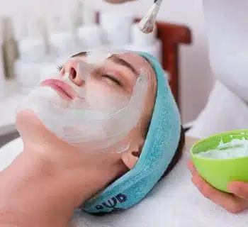 woman lying on blue towel with white cream on face